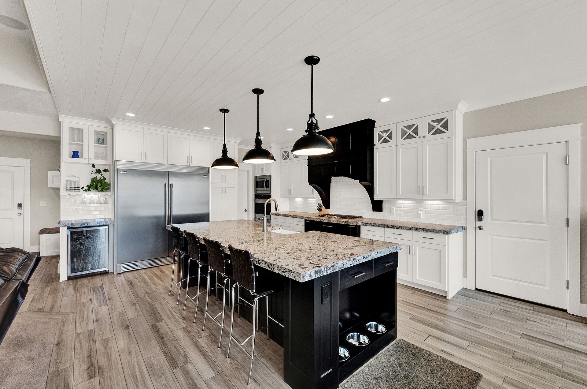 A kitchen with white cabinets , granite counter tops , stainless steel appliances and a large island.