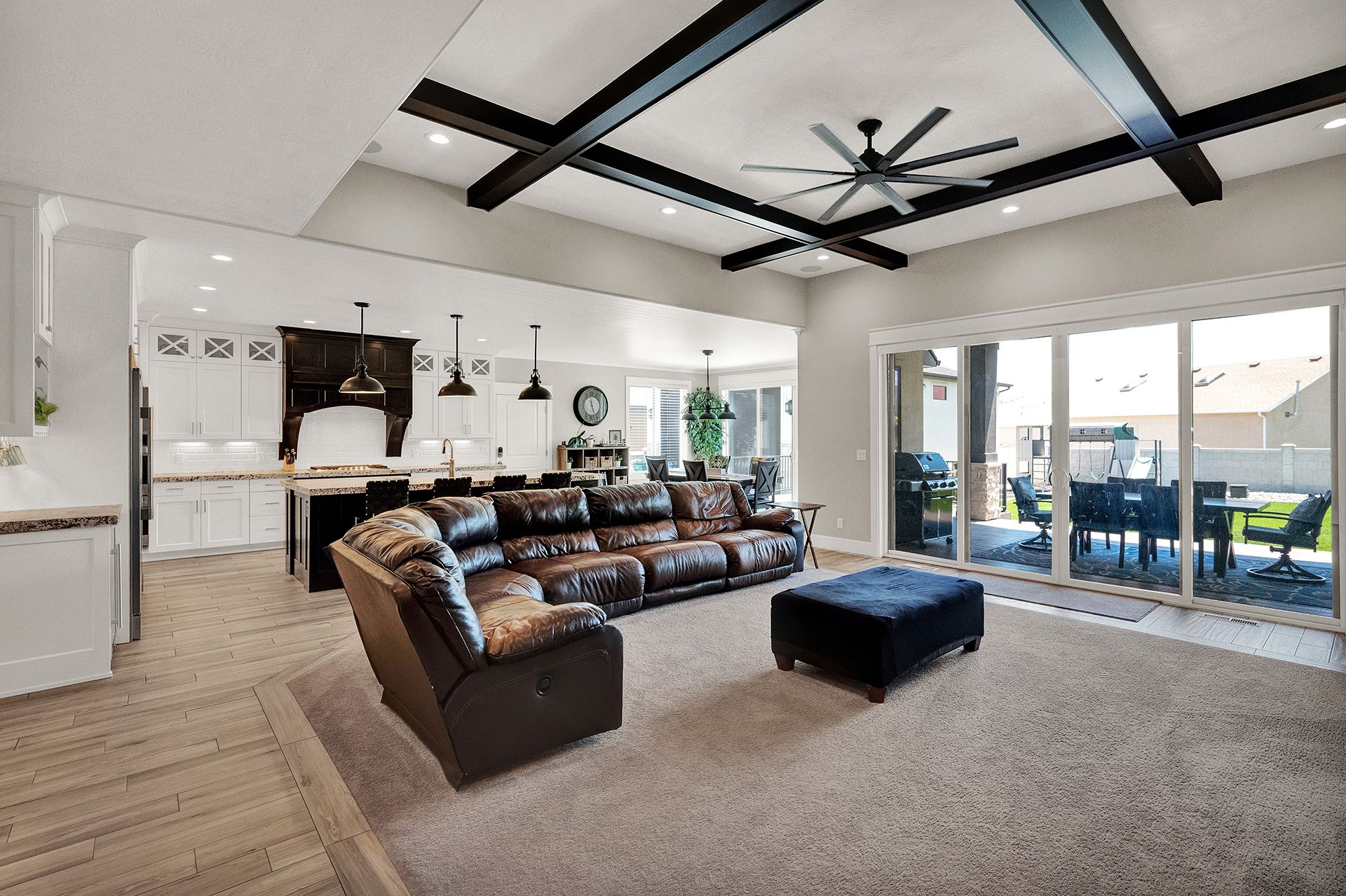 A living room with a couch , chair , ottoman and ceiling fan.