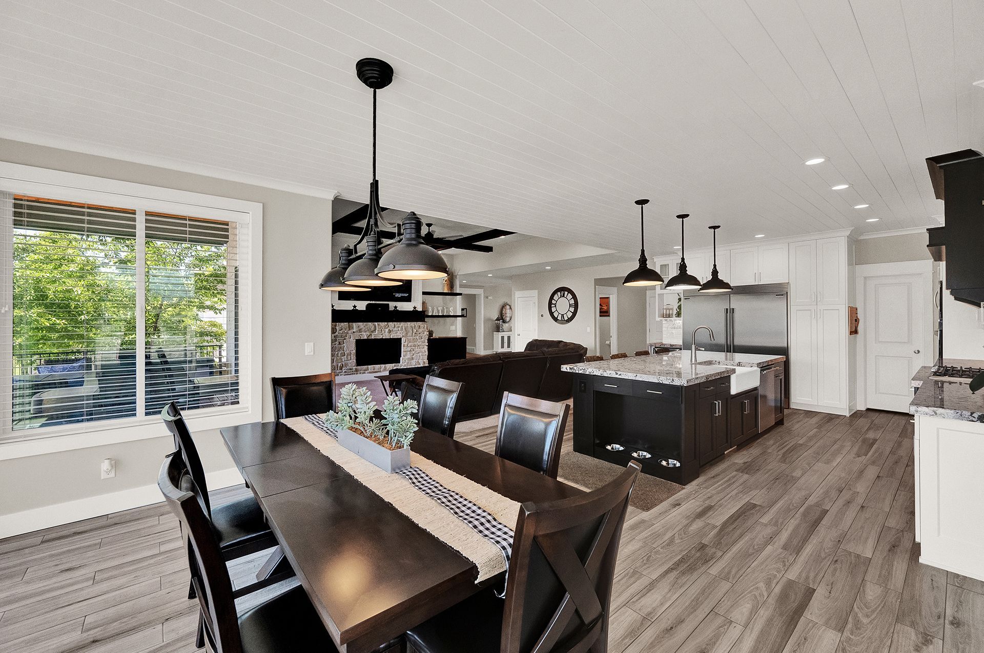 A dining room with a table and chairs and a kitchen in the background.