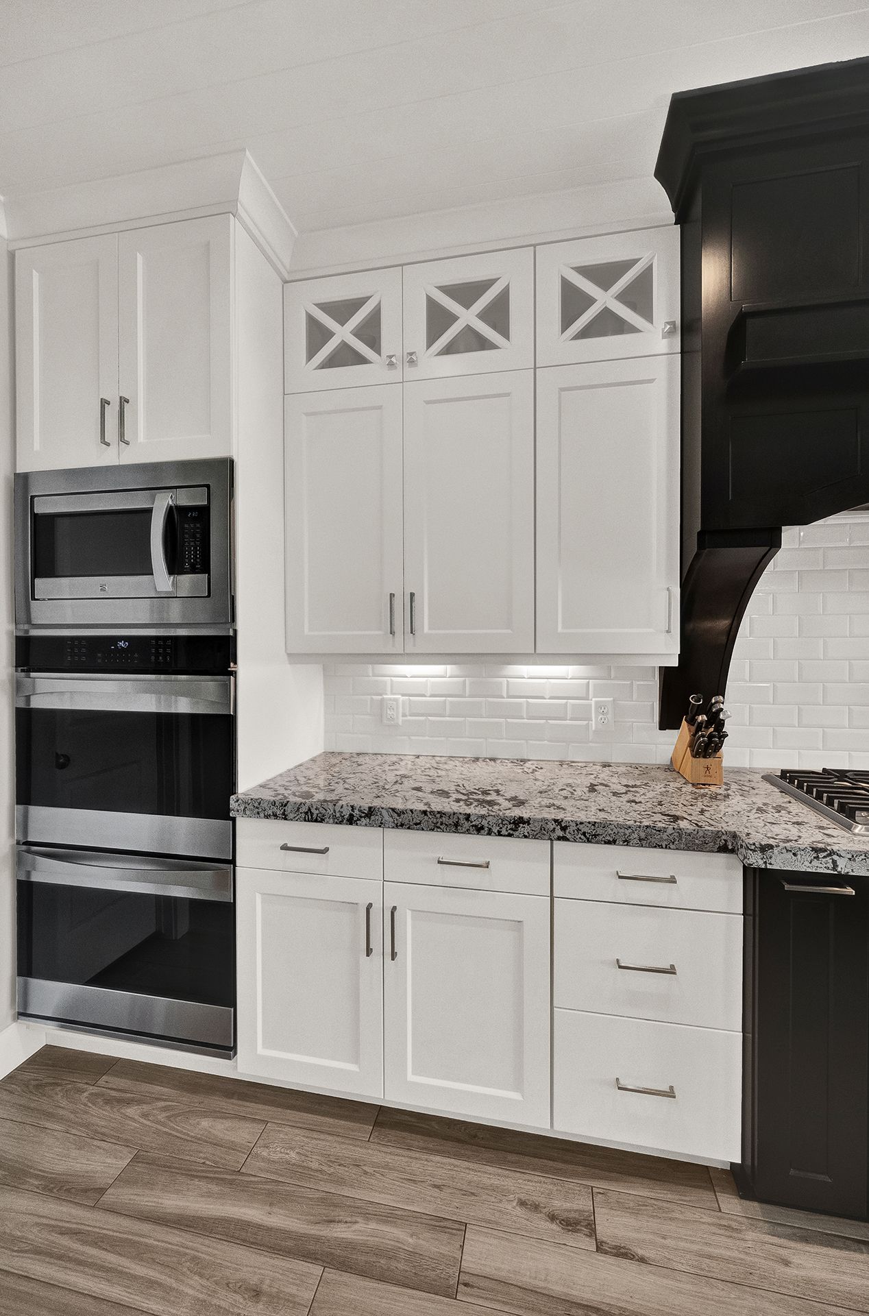 A kitchen with white cabinets , black appliances and granite counter tops.