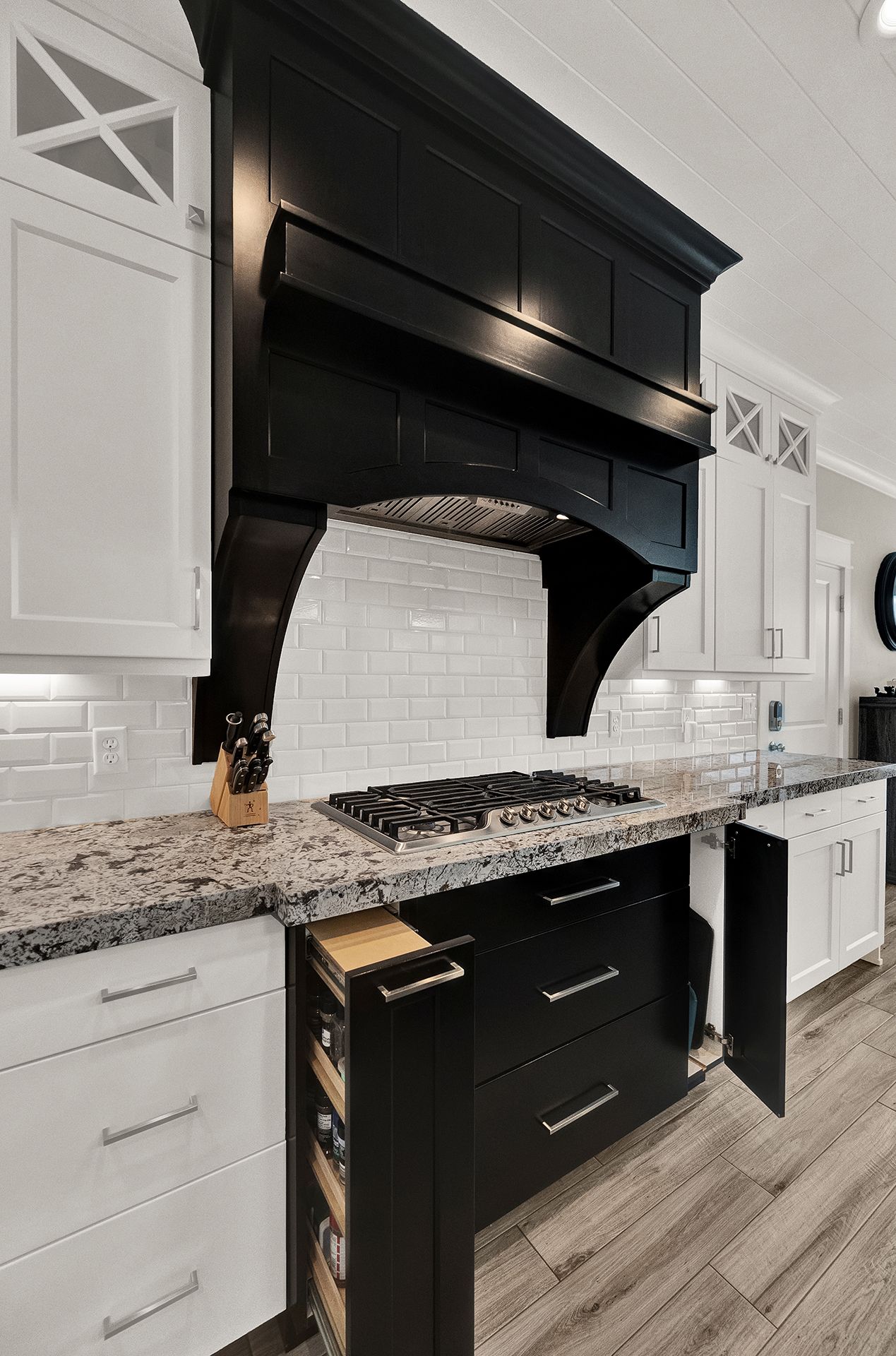 A kitchen with black cabinets and white cabinets and a stove top oven.
