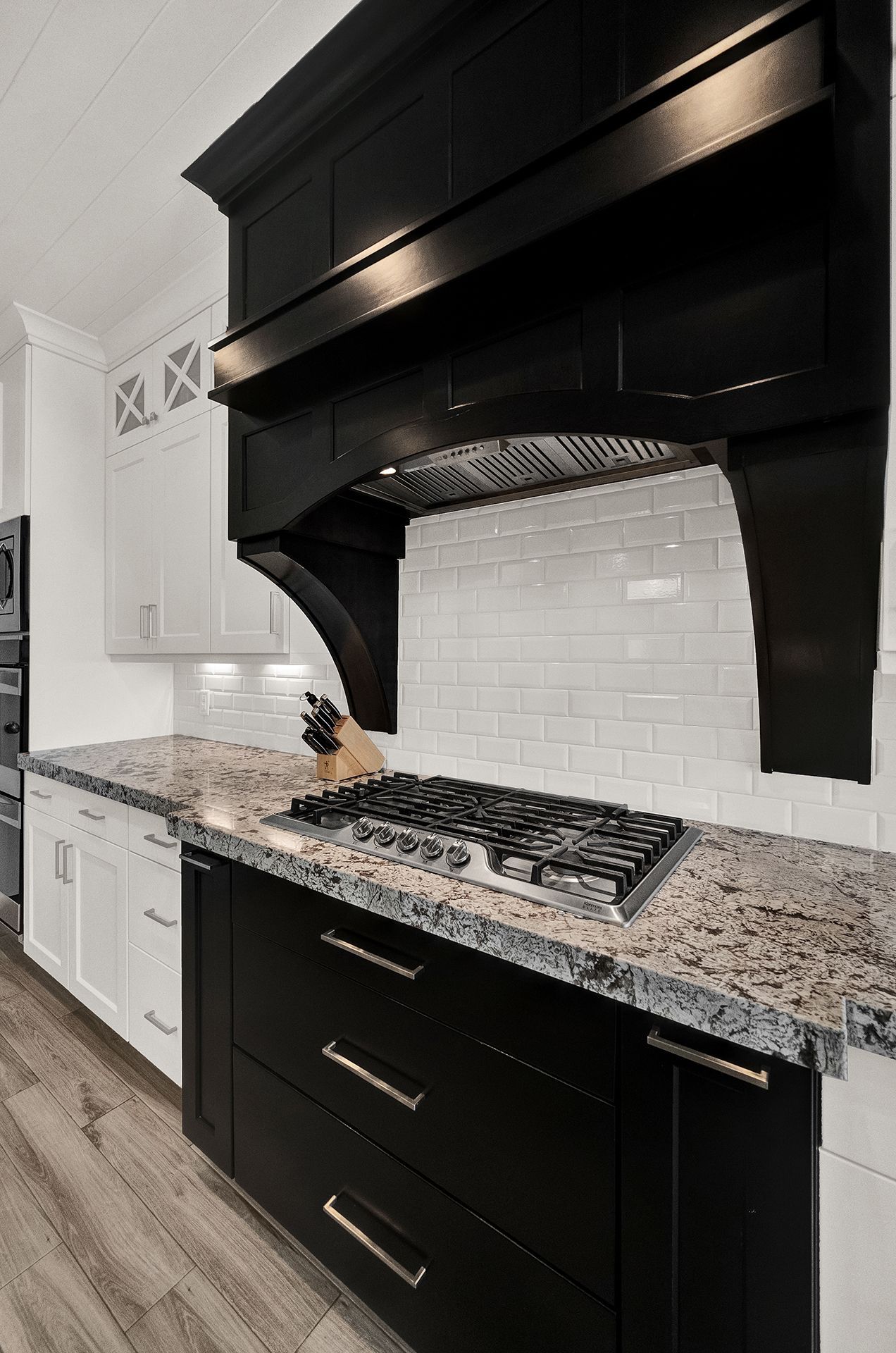 A kitchen with black cabinets , granite counter tops , and a stove top oven.