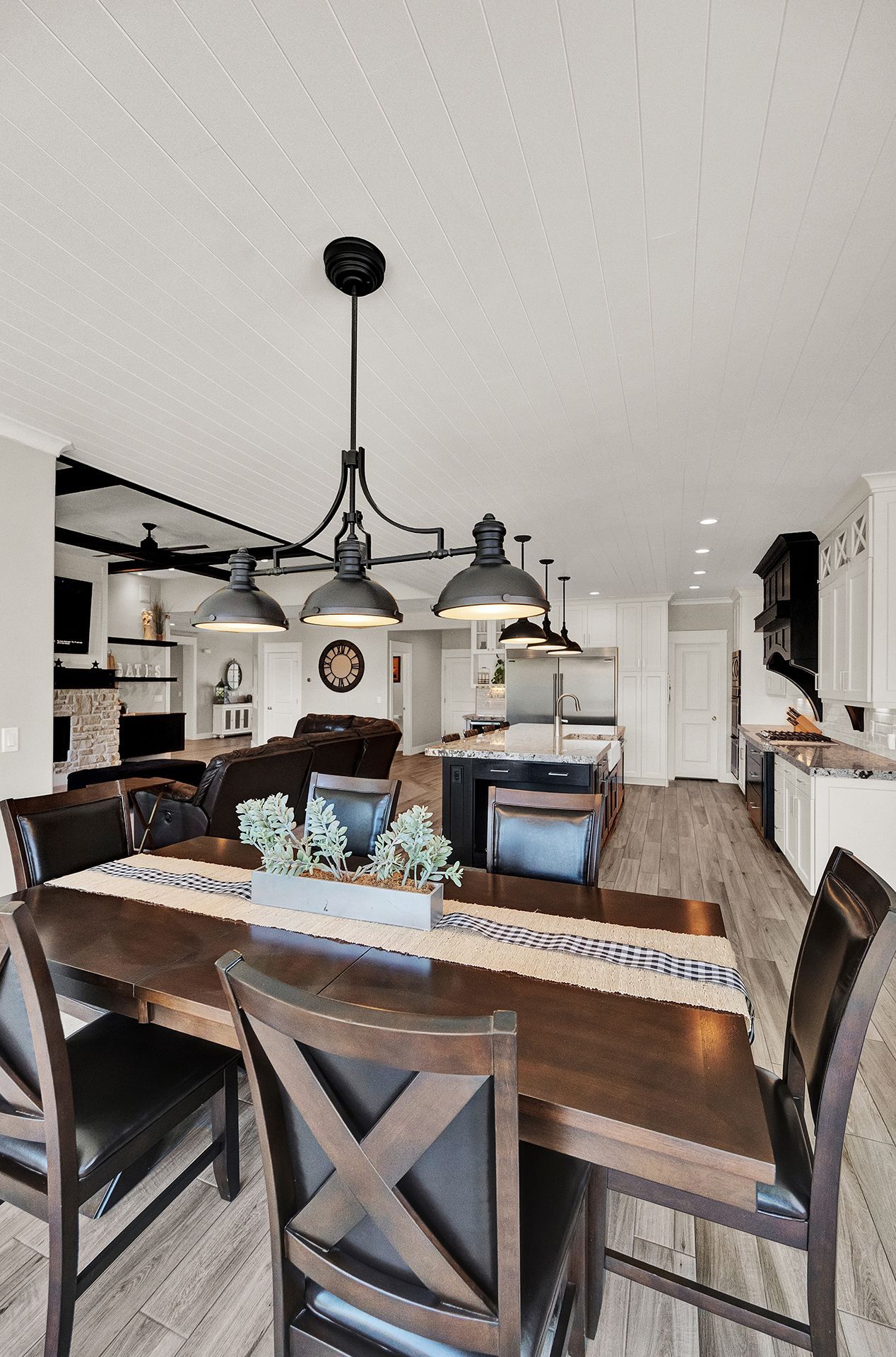 A dining room with a wooden table and chairs and a chandelier hanging from the ceiling.