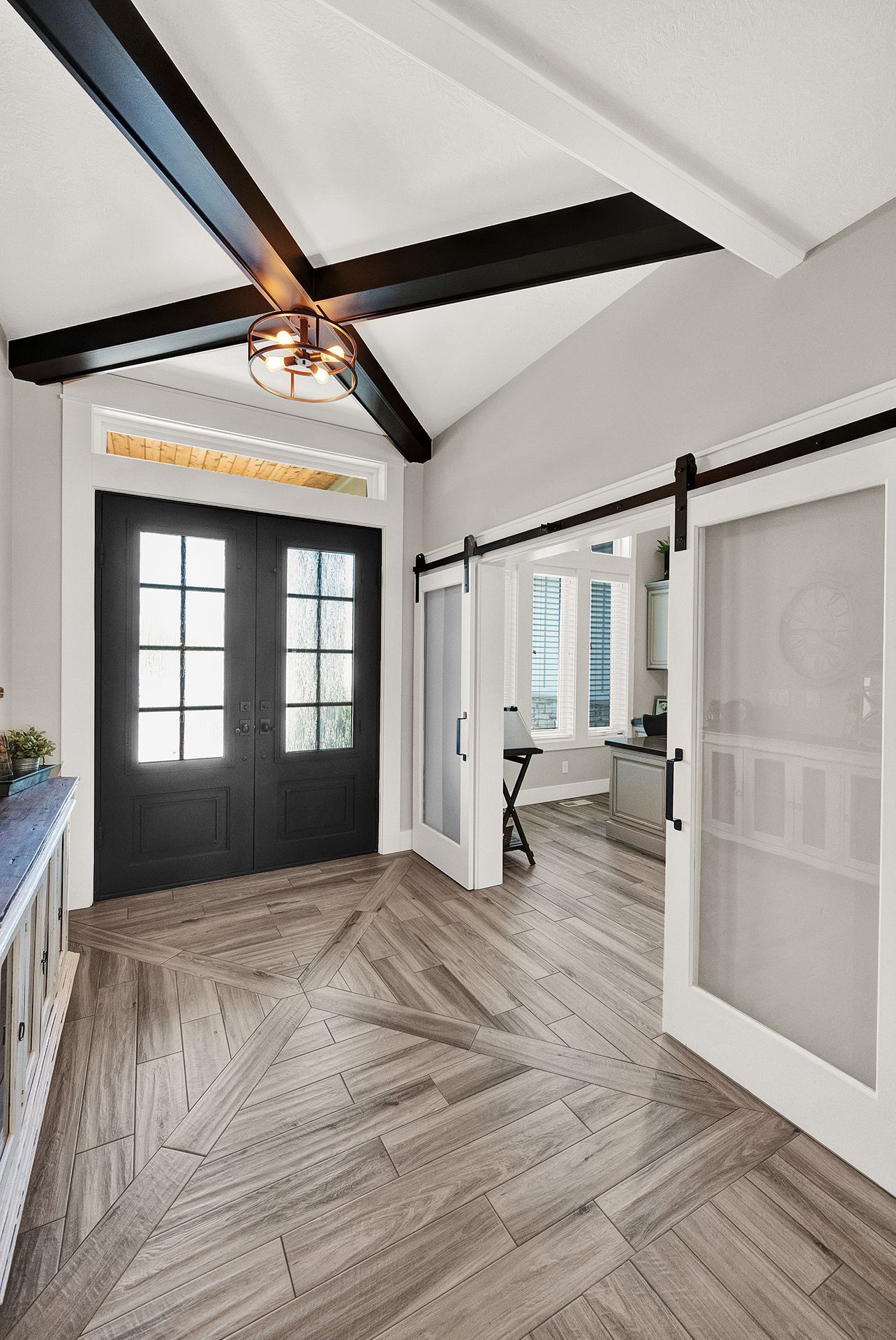A hallway with sliding barn doors and a black door.