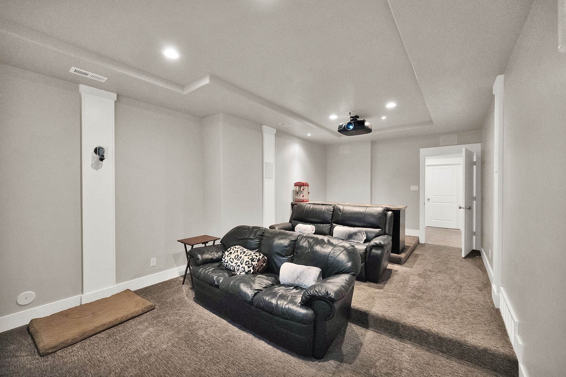 A living room with a couch and a projector on the ceiling.