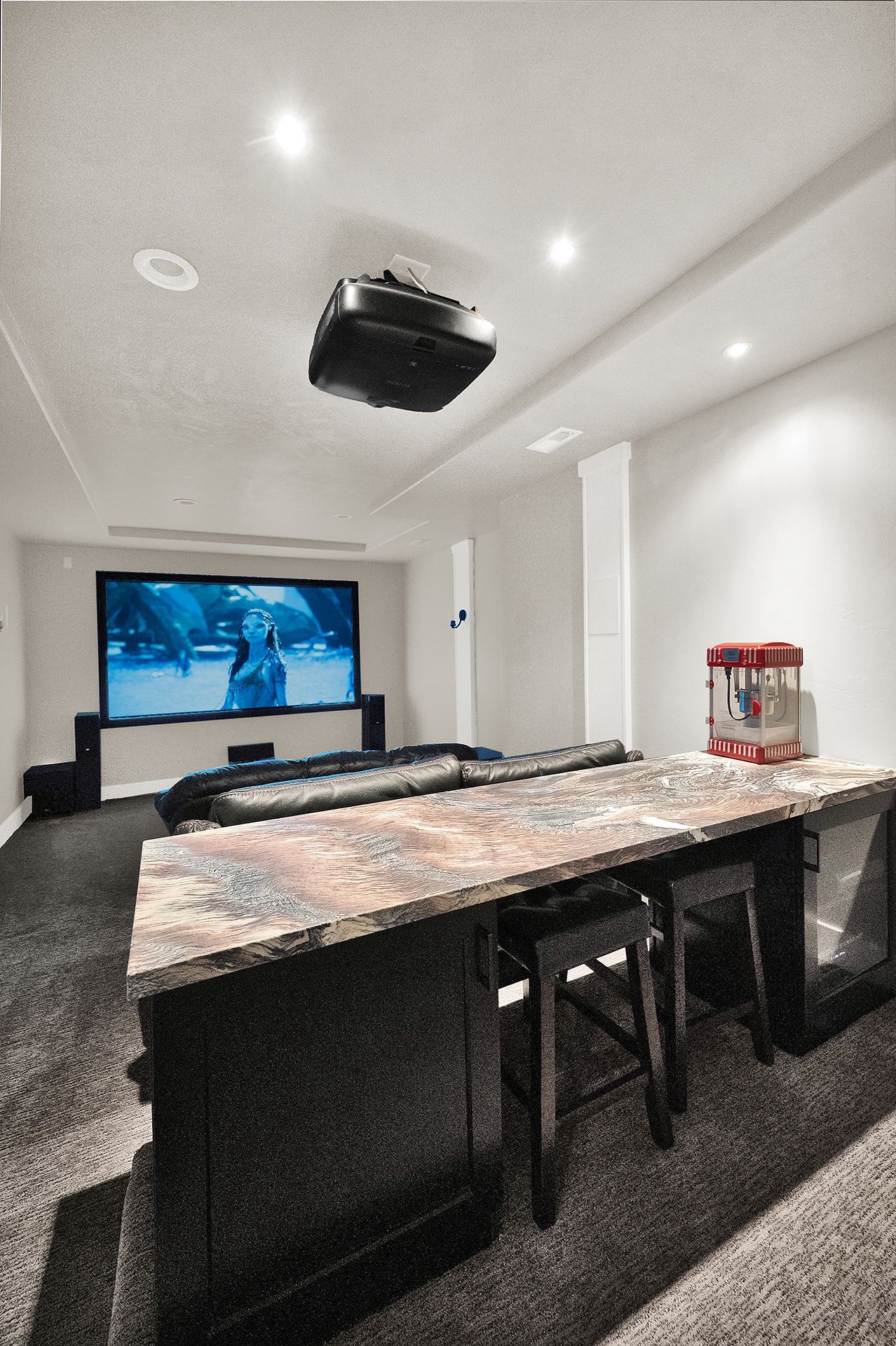 A home theater with a large screen and a popcorn machine.