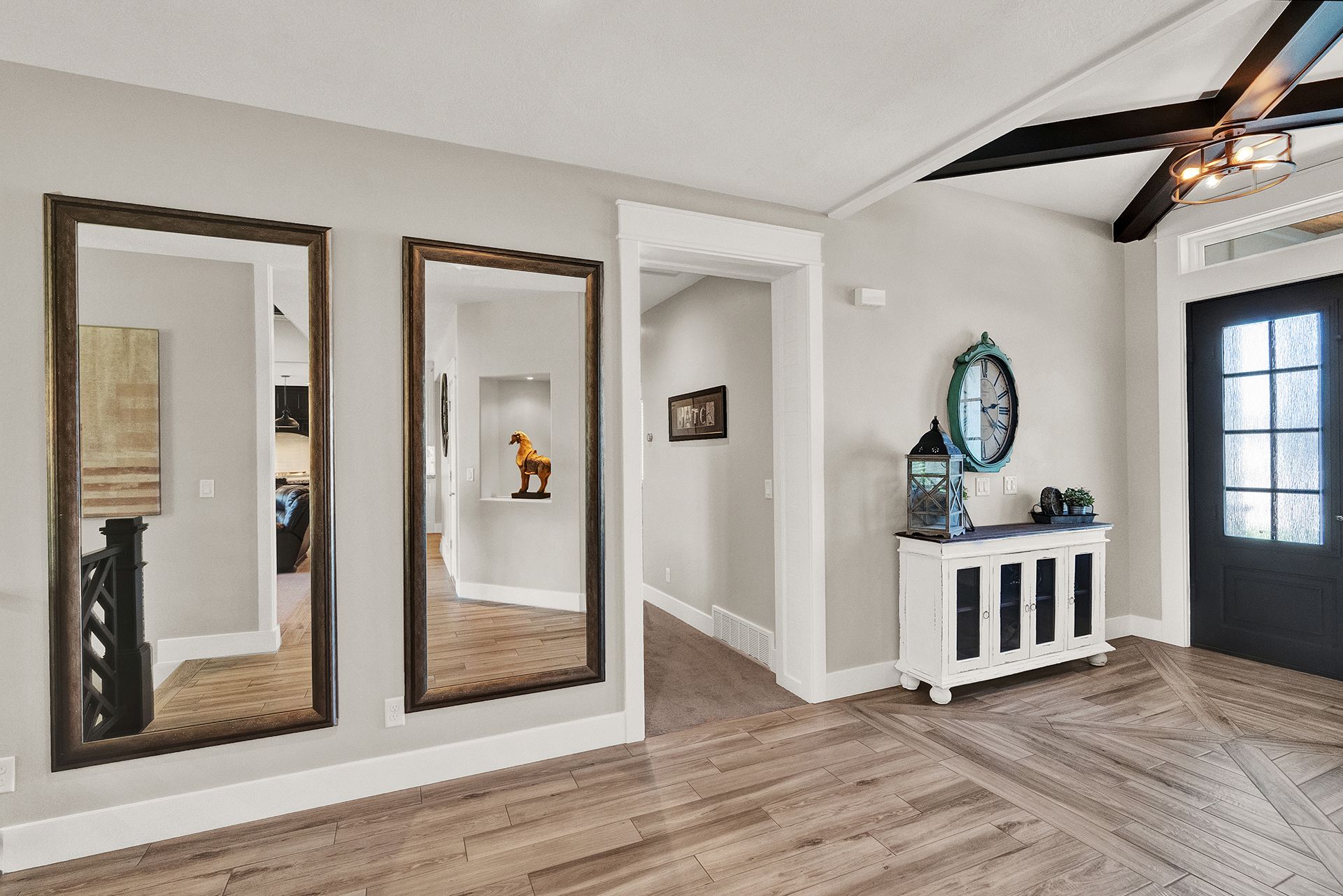 A hallway with three mirrors on the wall and a wooden floor.