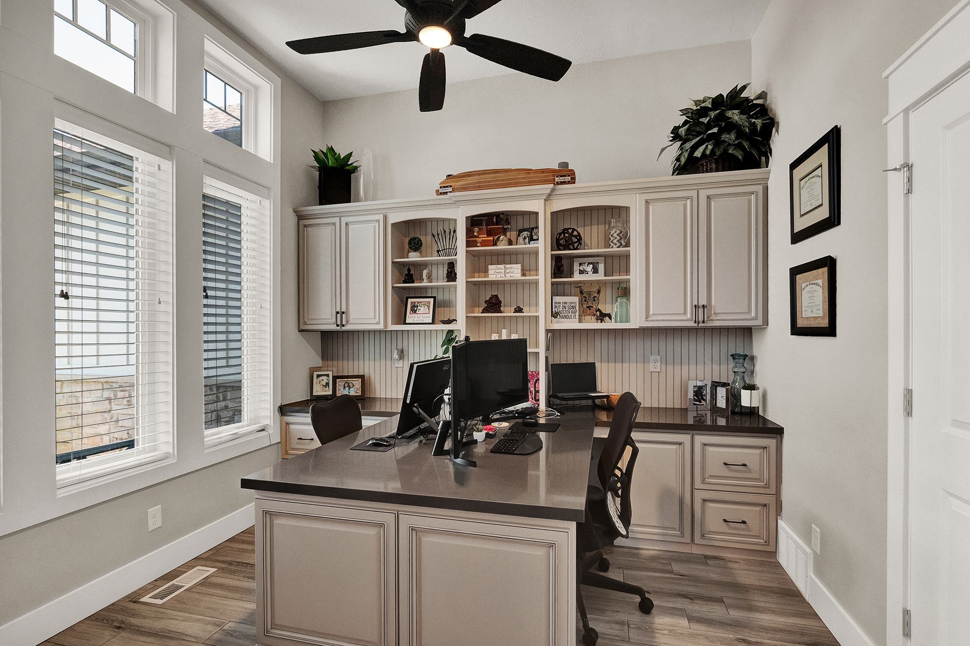 A home office with a ceiling fan and a desk with a computer on it.