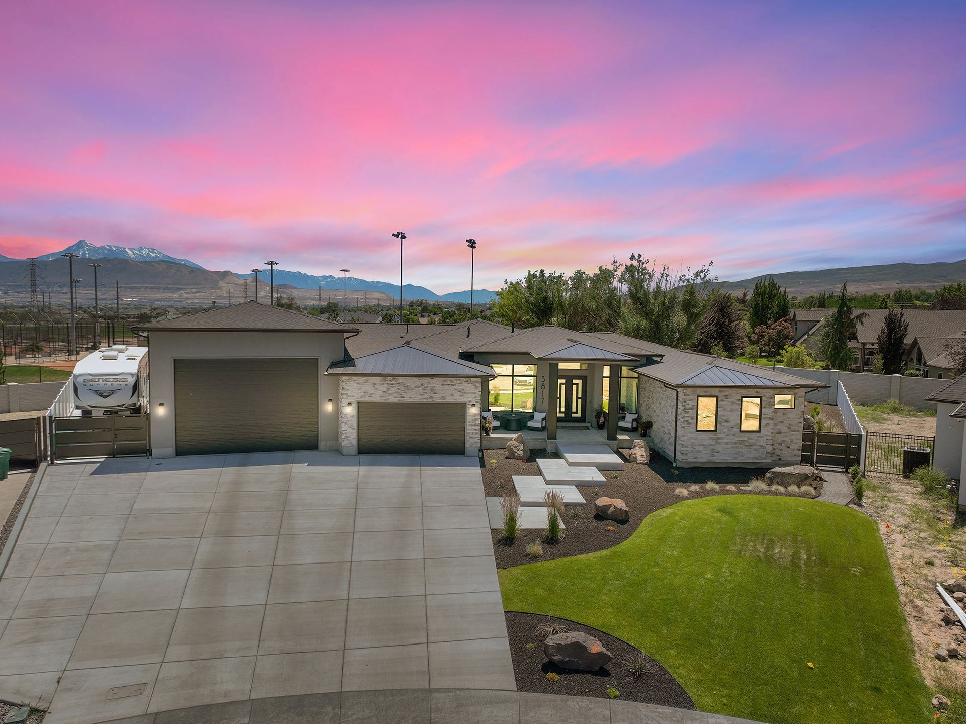 An aerial view of a house with a garage and a sunset in the background.