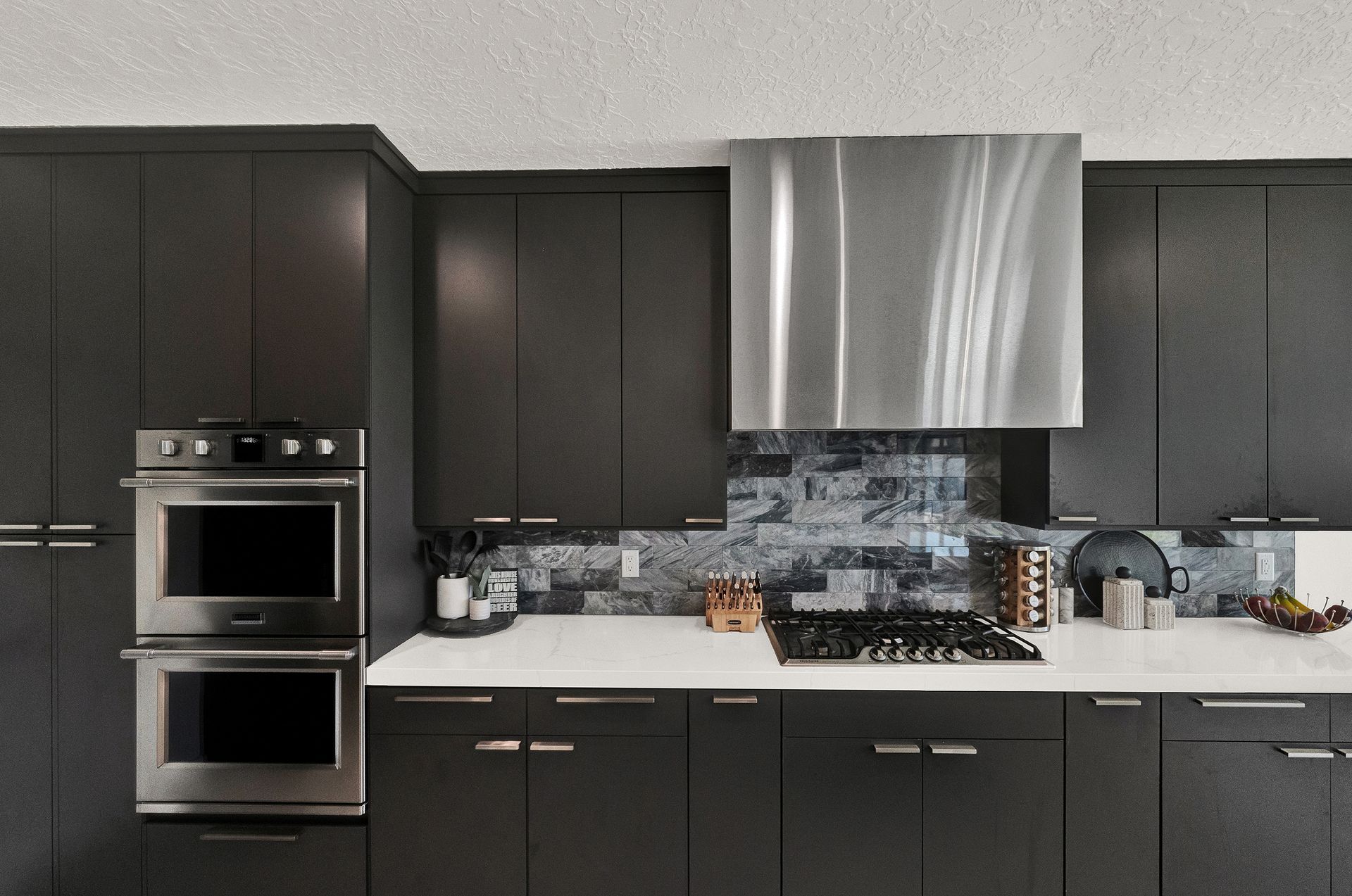 A kitchen with black cabinets and stainless steel appliances