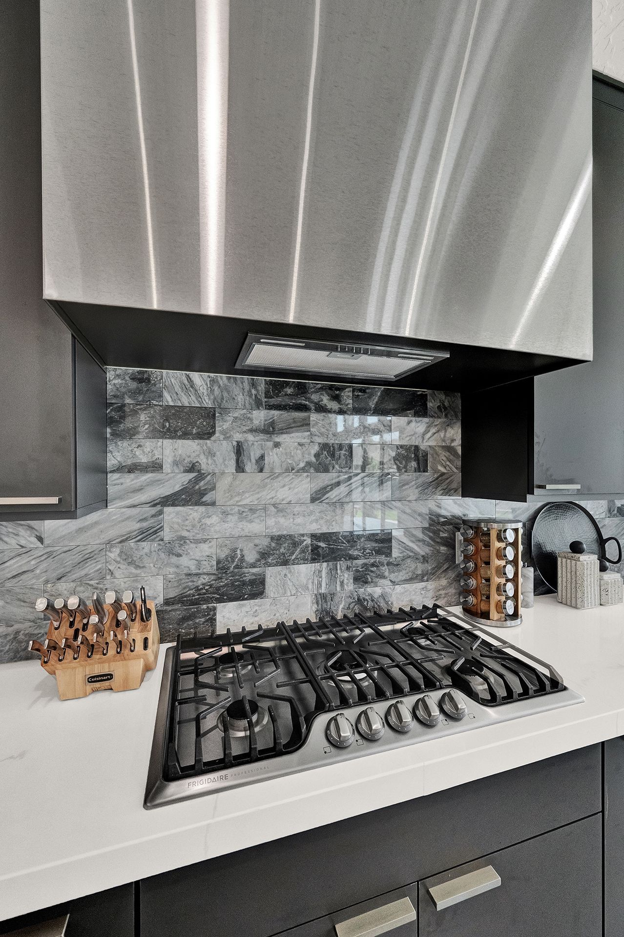 A kitchen with a stove top oven and a stainless steel hood.