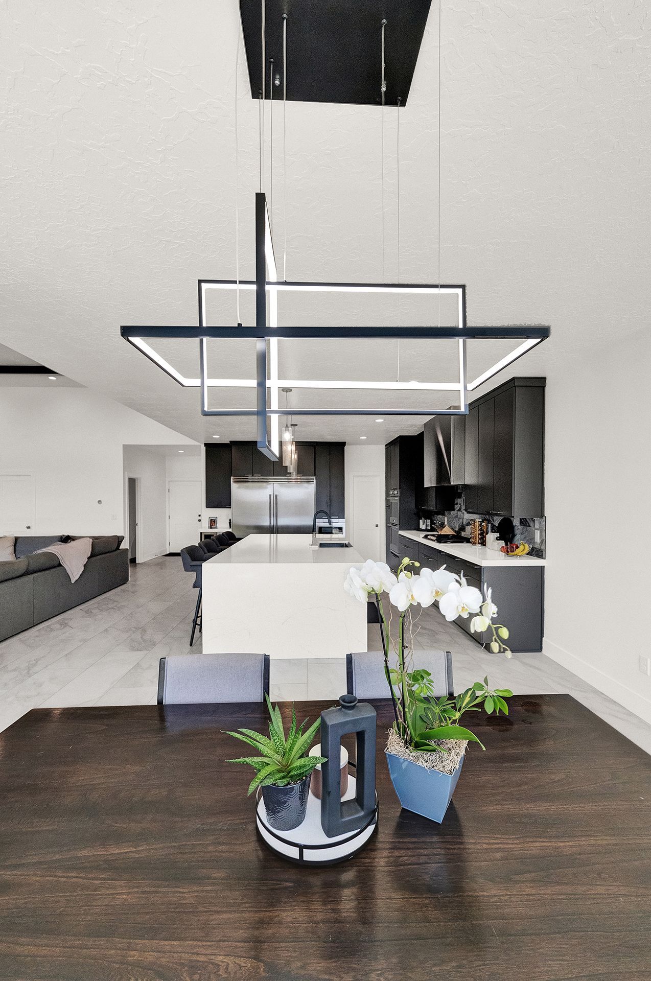 A dining room table with a potted plant on it in front of a kitchen.