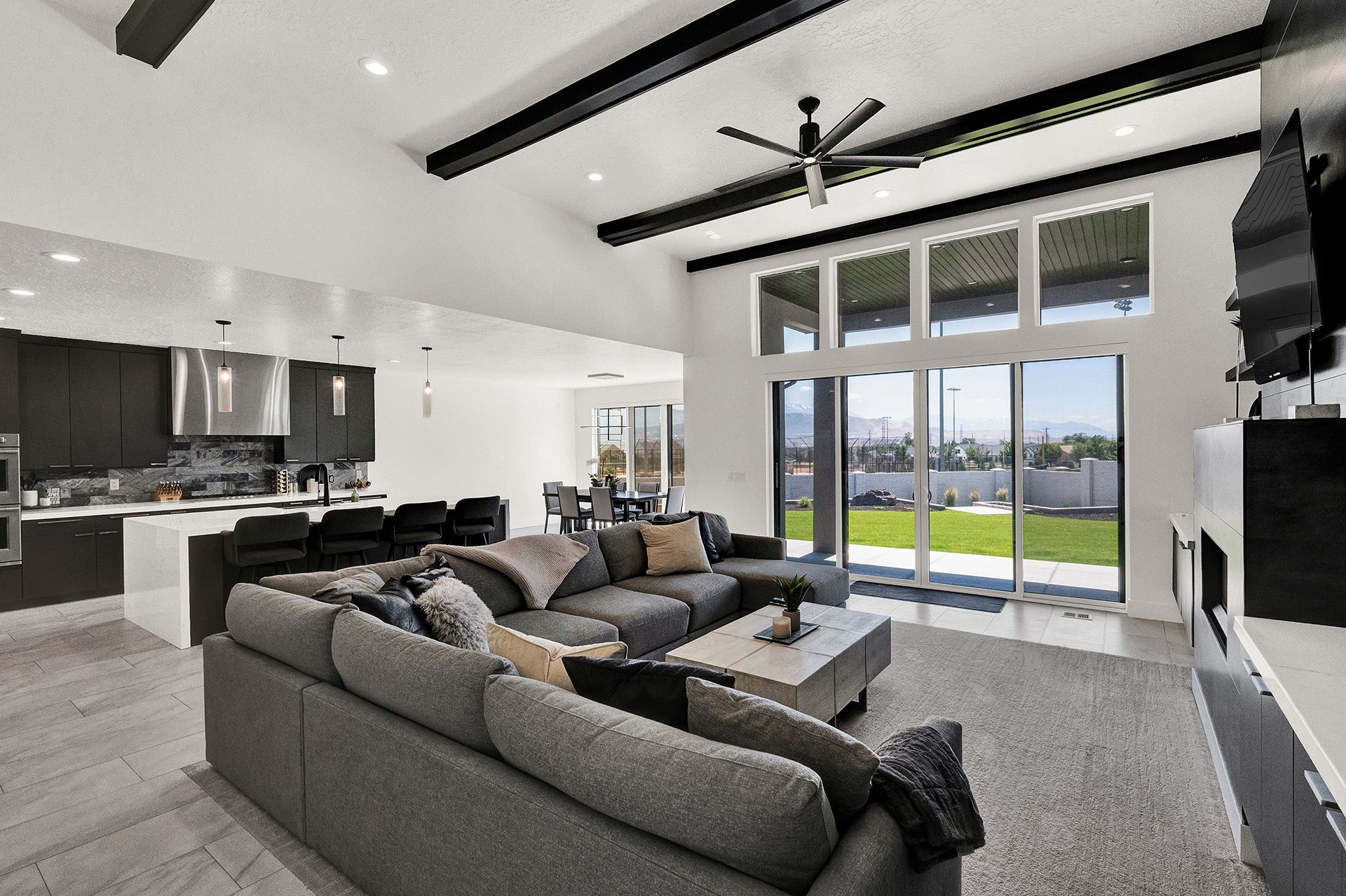 A living room with a large sectional couch and a ceiling fan
