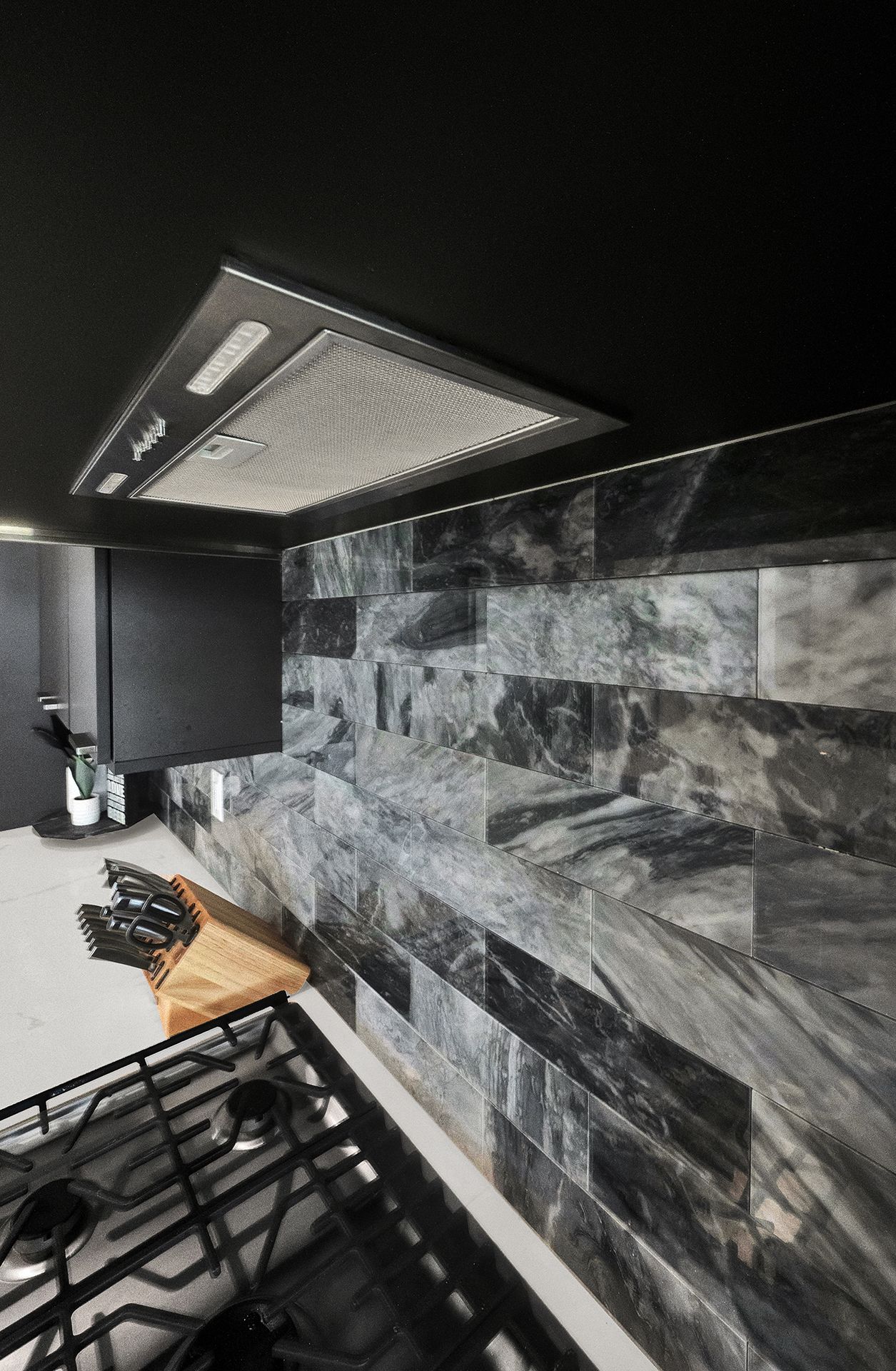 A kitchen with a stove and a hood above it.