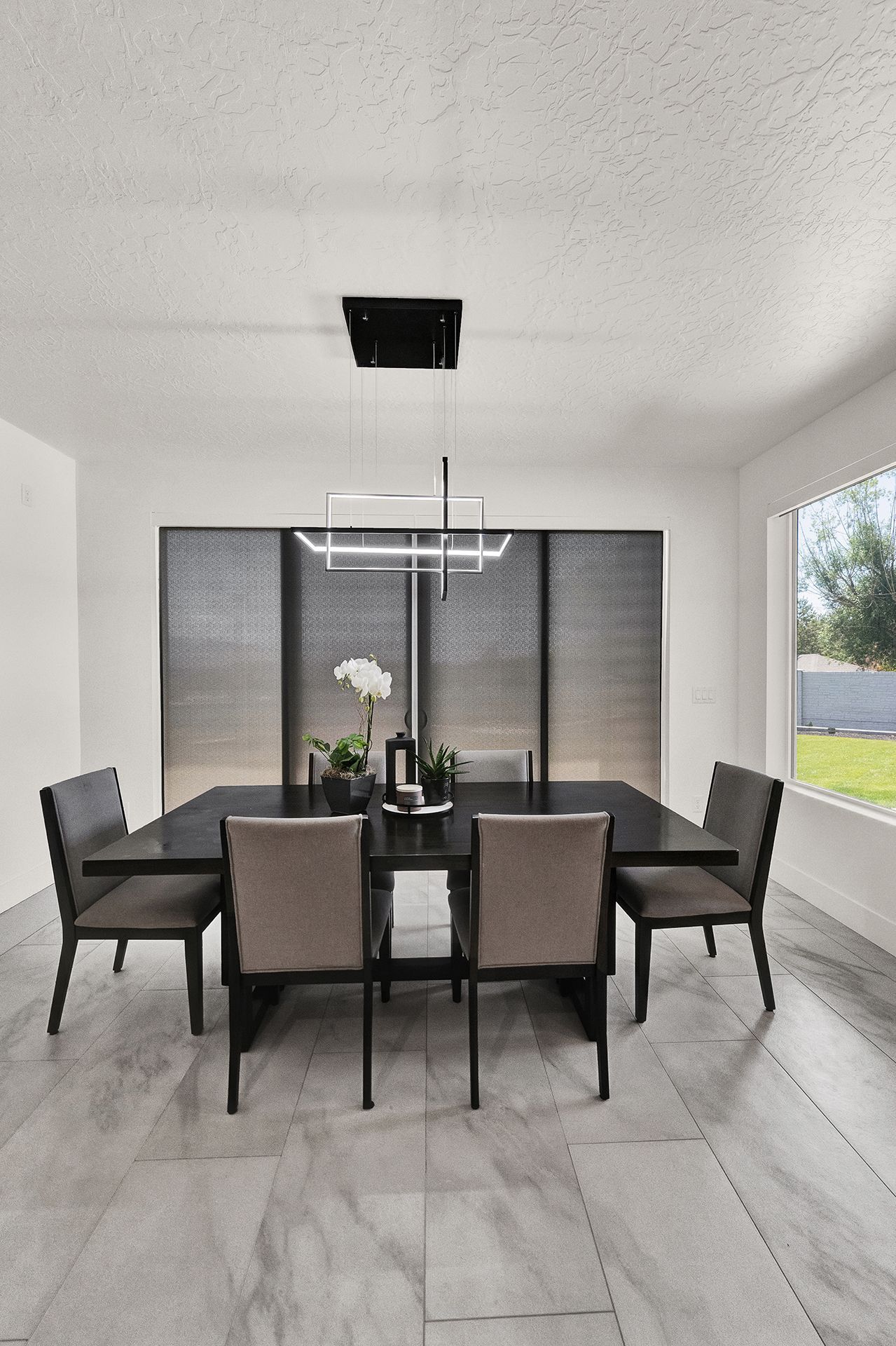 A dining room with a table and chairs and a chandelier hanging from the ceiling.