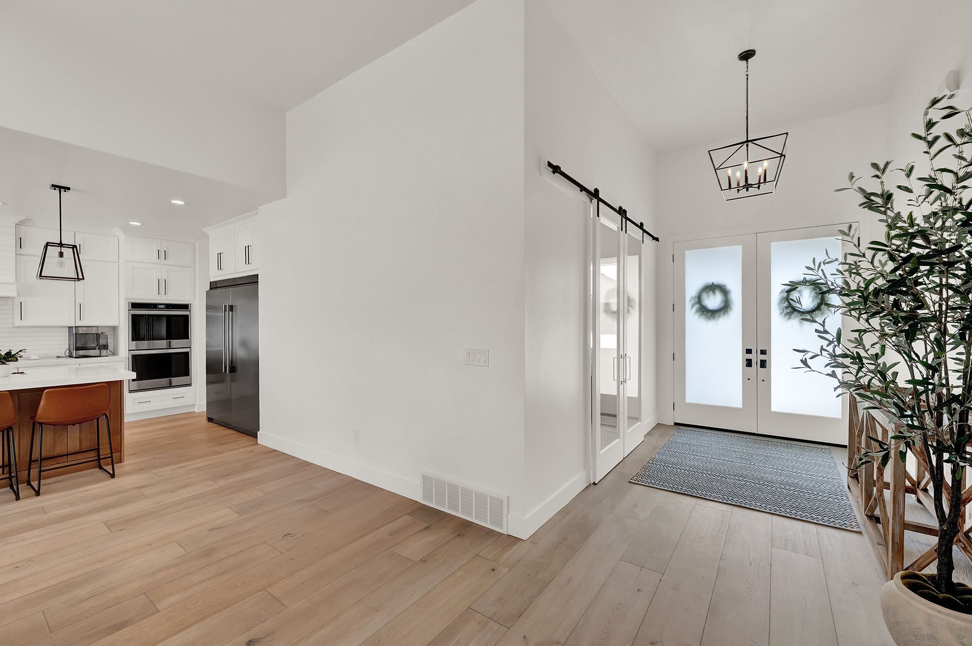 A hallway in a house with a sliding barn door leading to the front door.