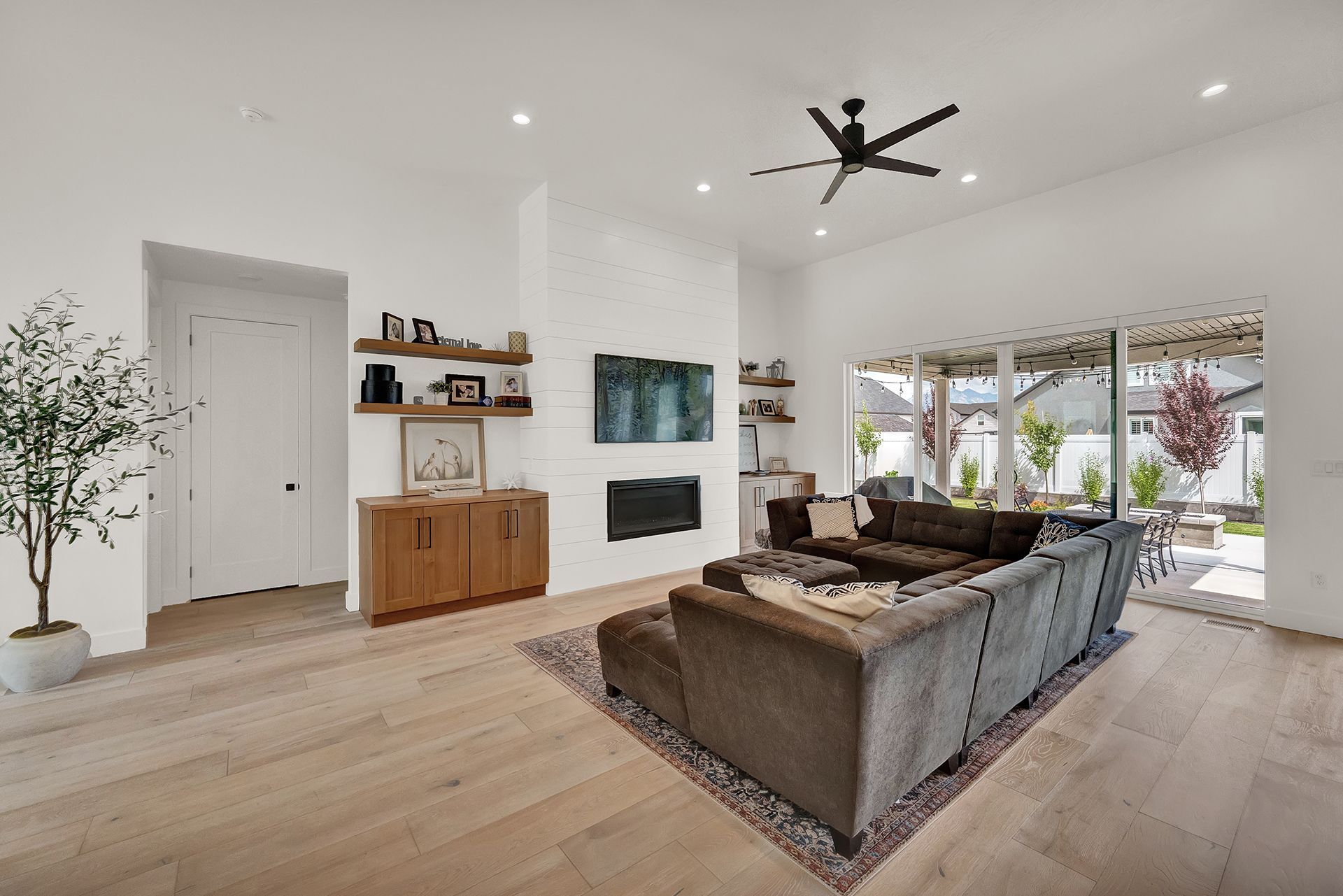 A living room with a couch , fireplace , television and ceiling fan.