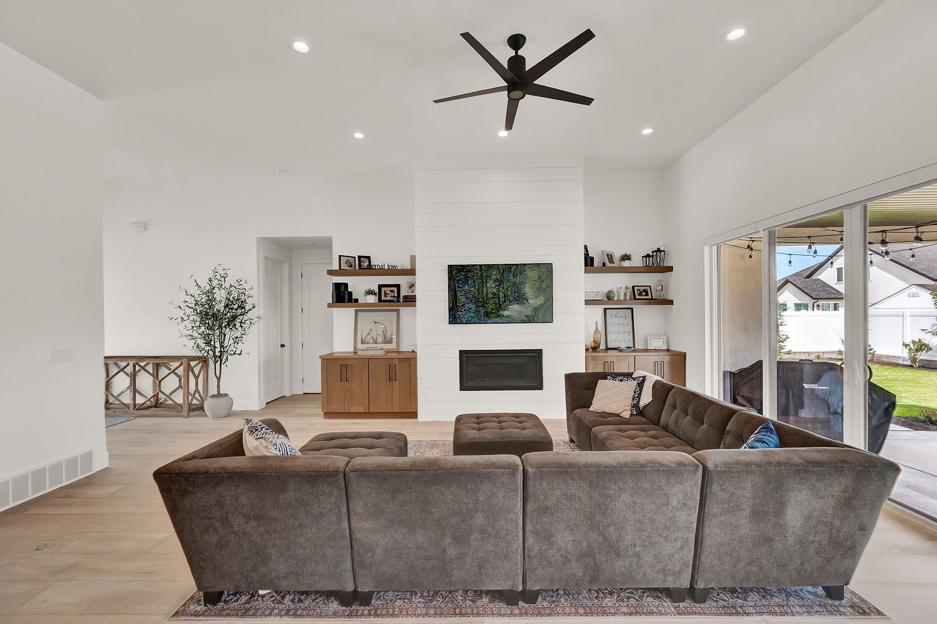 A living room with a couch , fireplace and ceiling fan