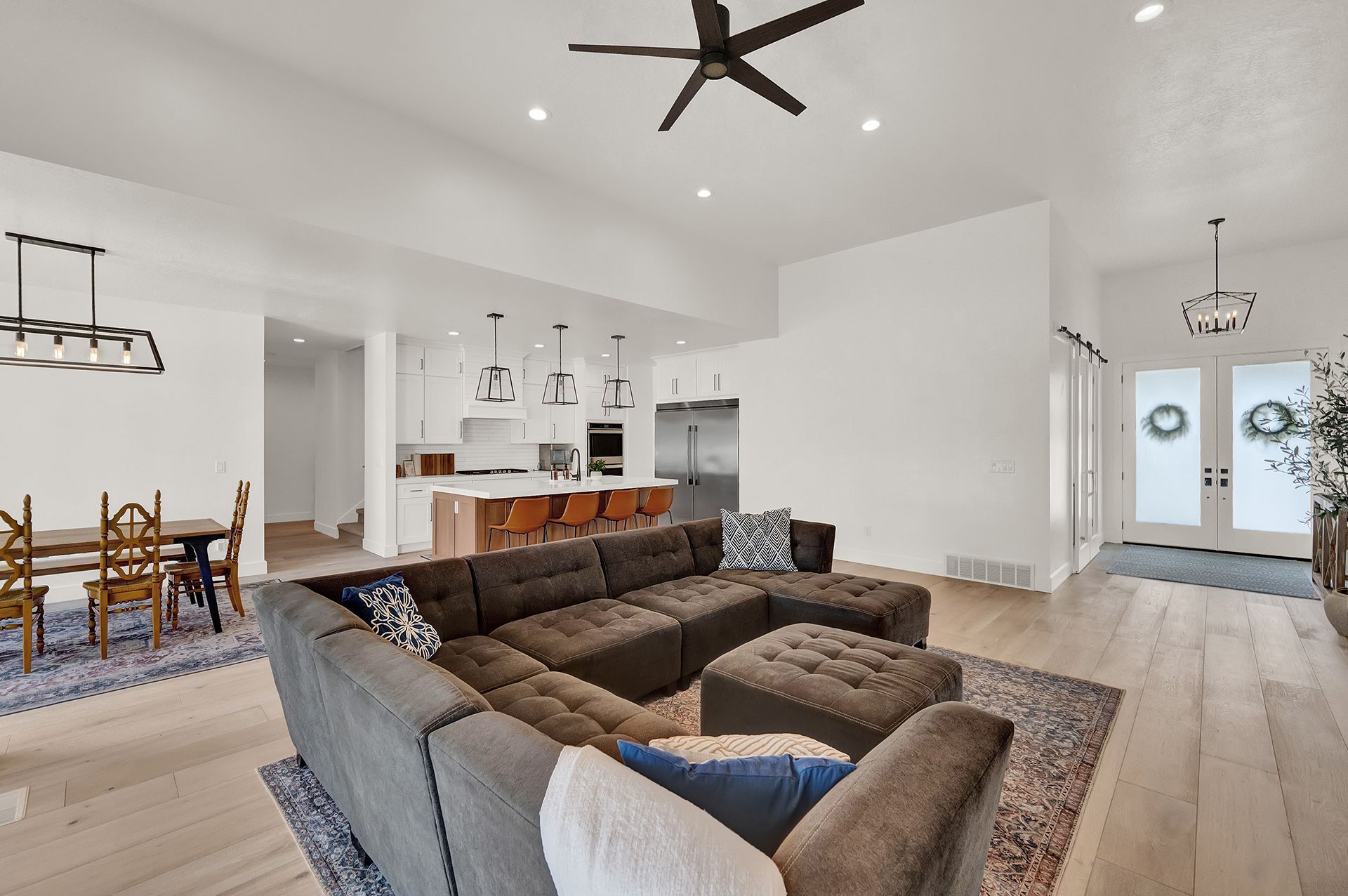 A living room with a large sectional couch and a ceiling fan.