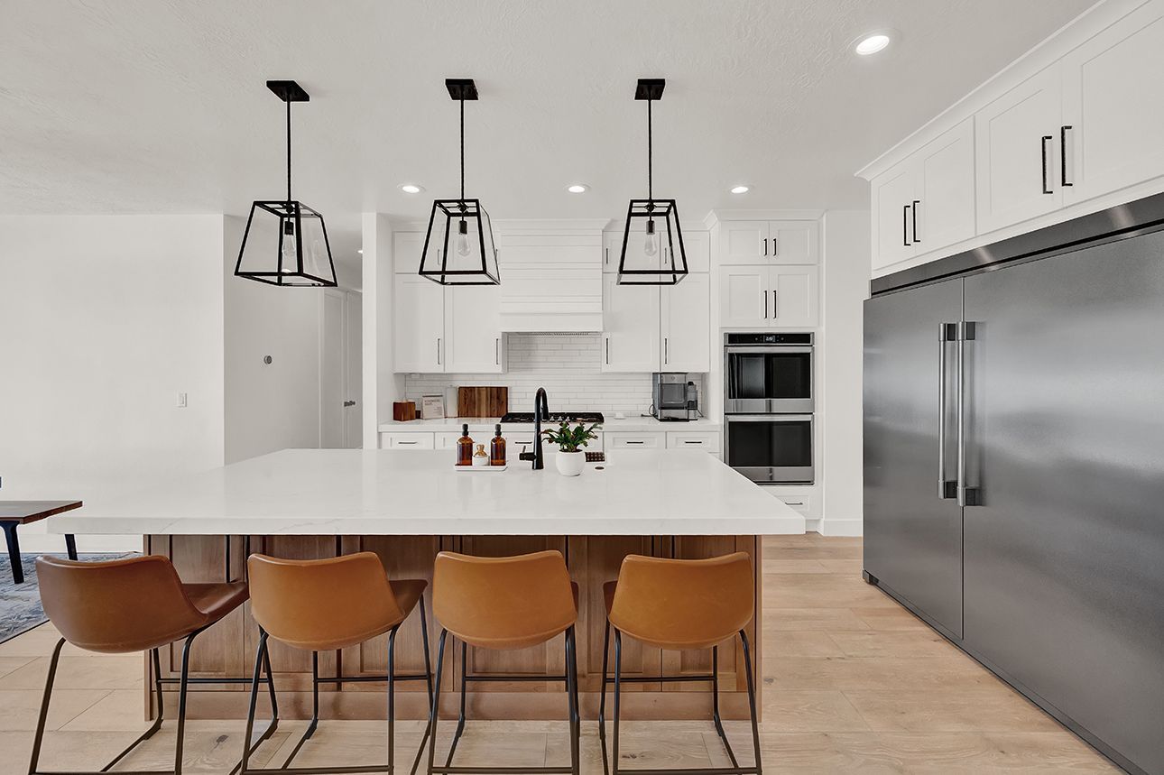 A kitchen with white cabinets , stainless steel appliances , and a large island.
