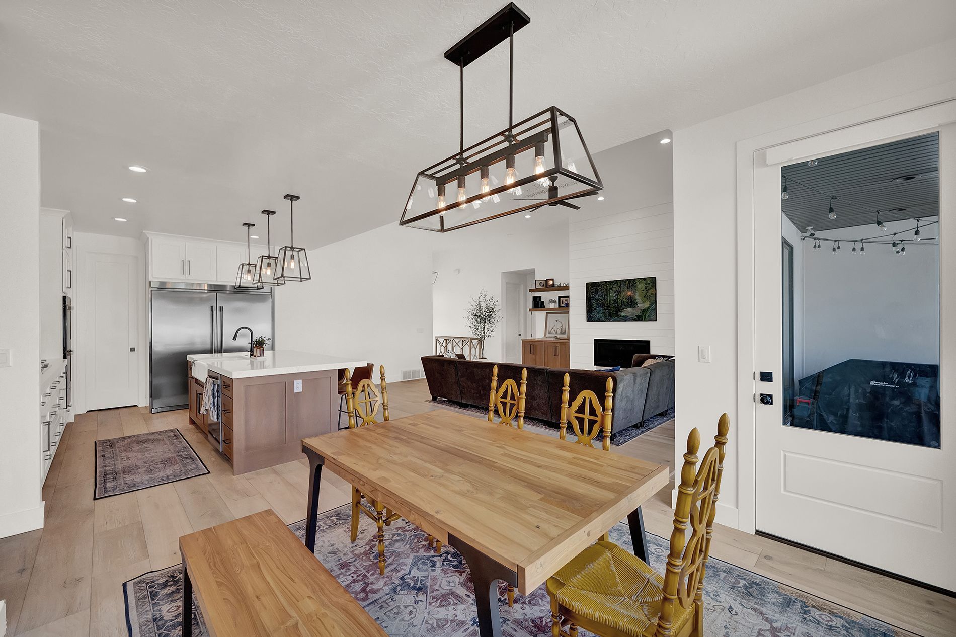 A dining room with a wooden table and chairs and a chandelier hanging from the ceiling.