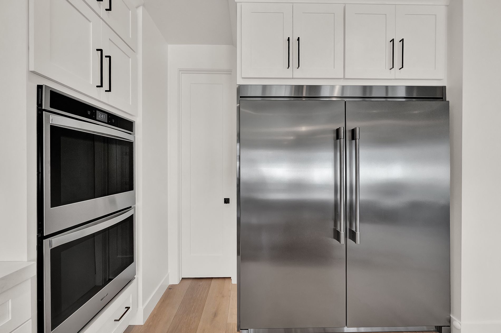 A kitchen with stainless steel appliances and white cabinets.