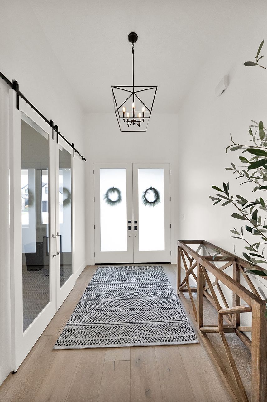 A hallway with a rug and a chandelier hanging from the ceiling.