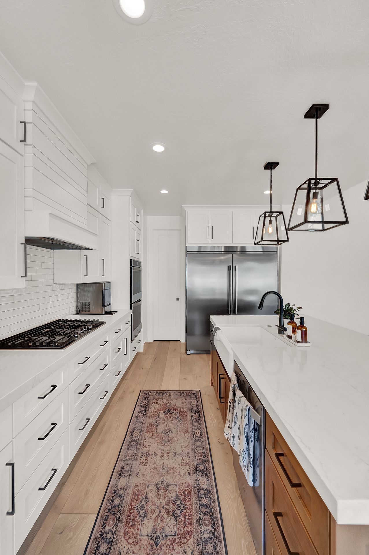 A long kitchen with white cabinets and a rug on the floor.