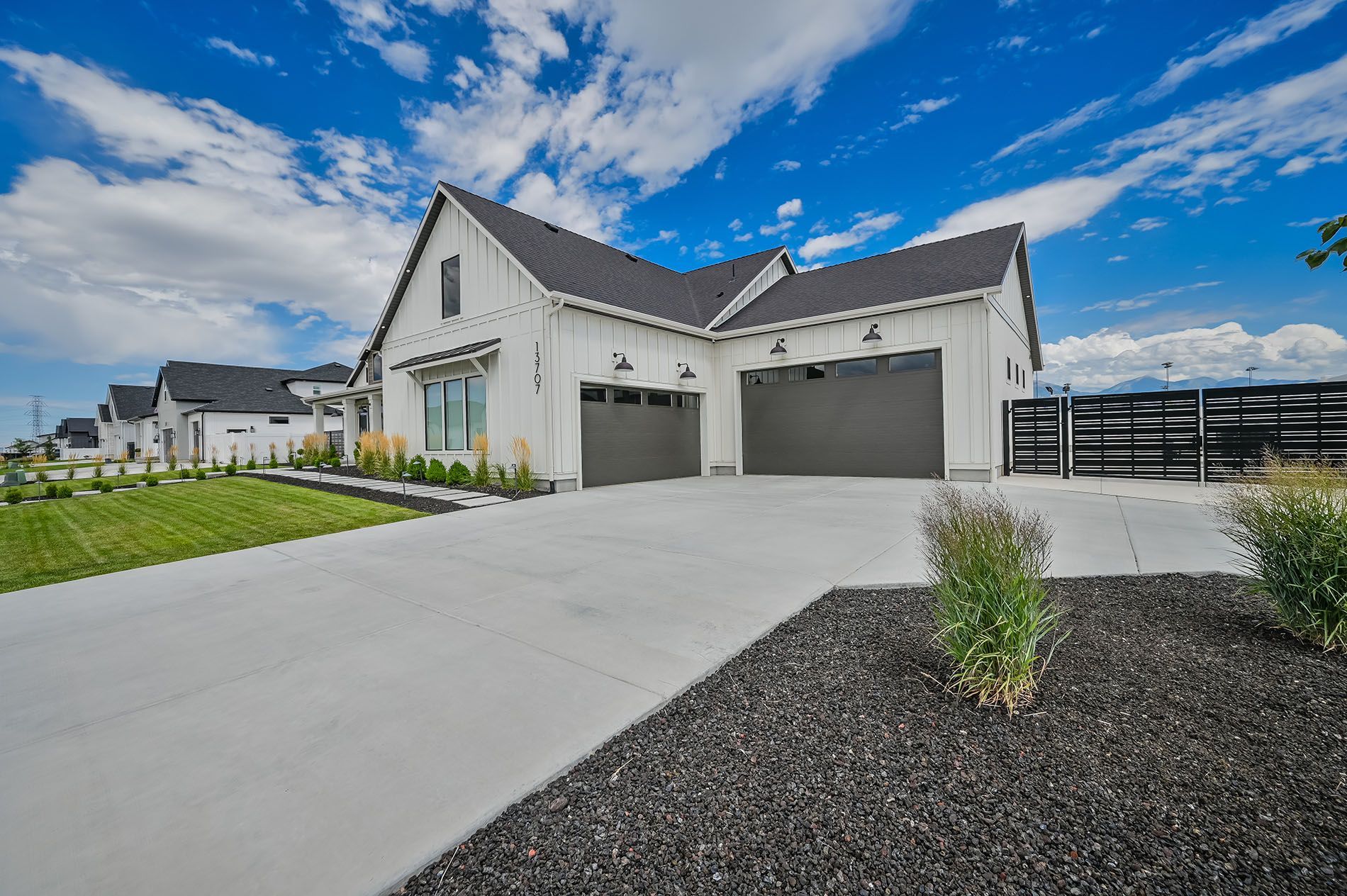 A large white house with two garages and a driveway.