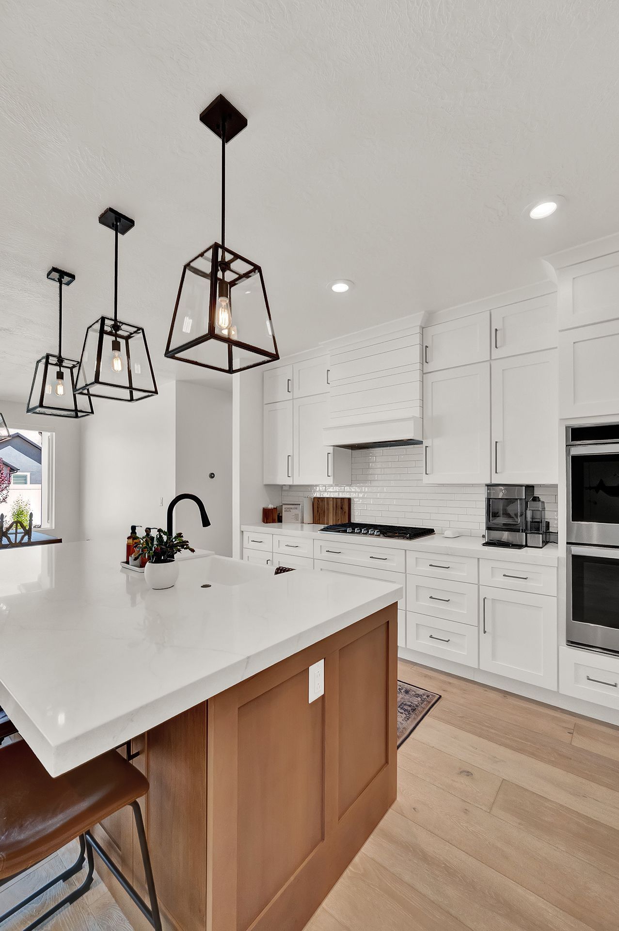 A kitchen with white cabinets and wooden cabinets and a large island.
