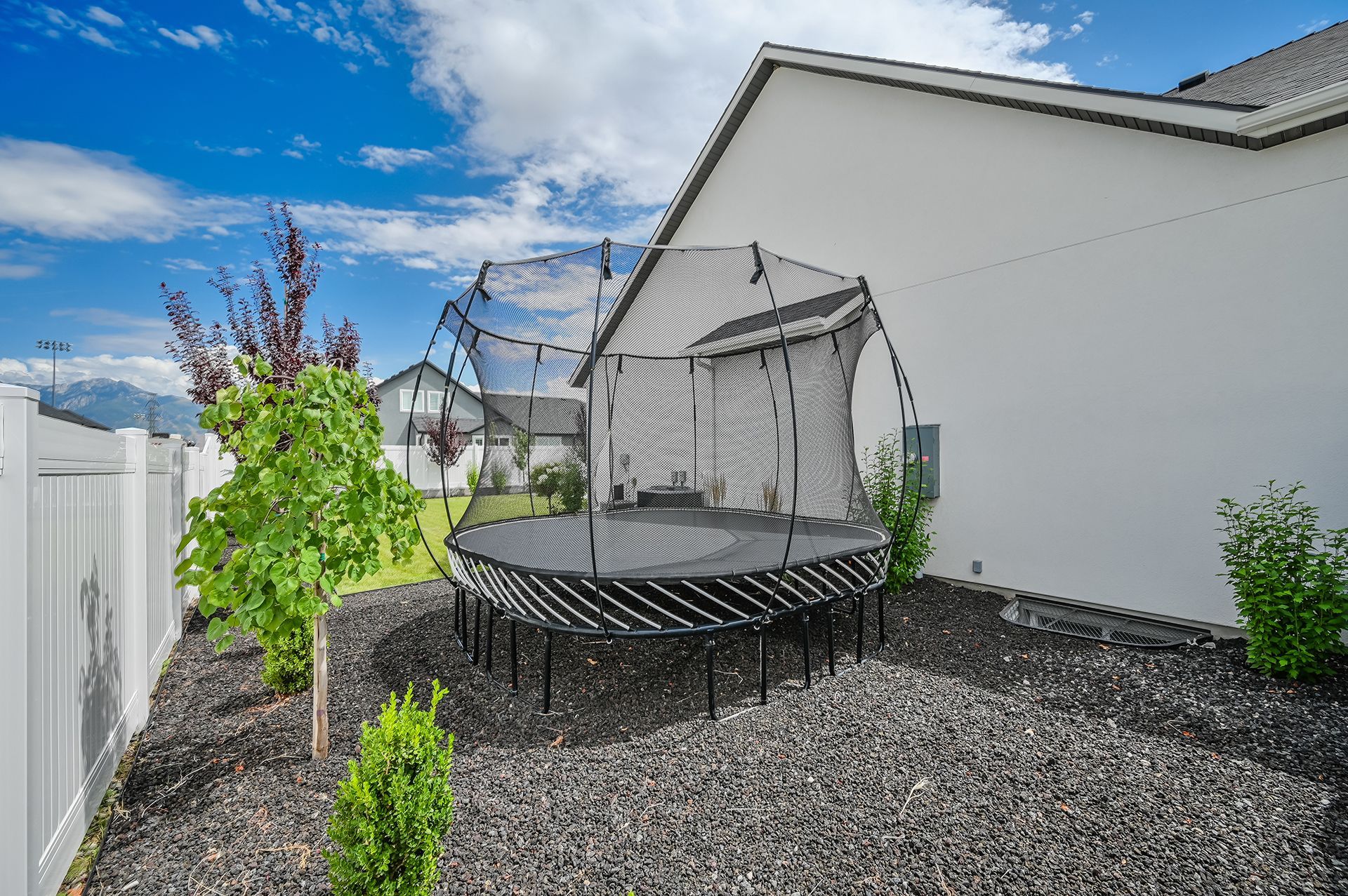 A trampoline is sitting in the backyard of a house.