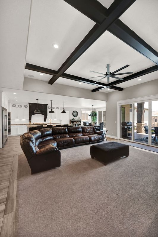 A living room with a couch , ottoman , and ceiling fan.