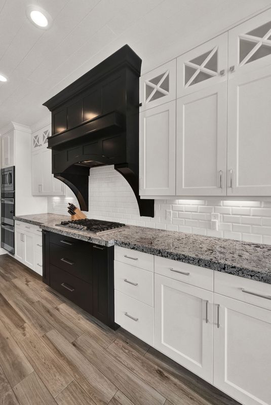 A kitchen with white cabinets and black appliances and granite counter tops.