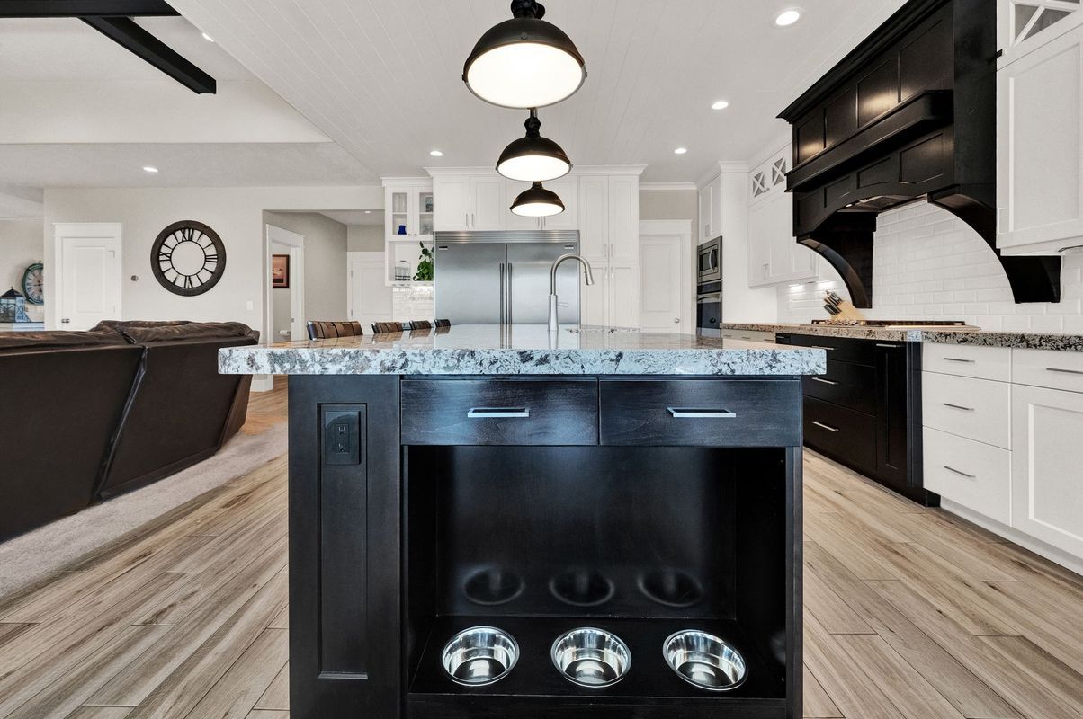 A kitchen with a black island and white cabinets