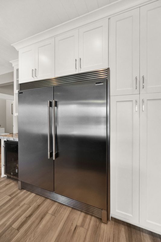 A kitchen with white cabinets and a stainless steel refrigerator.