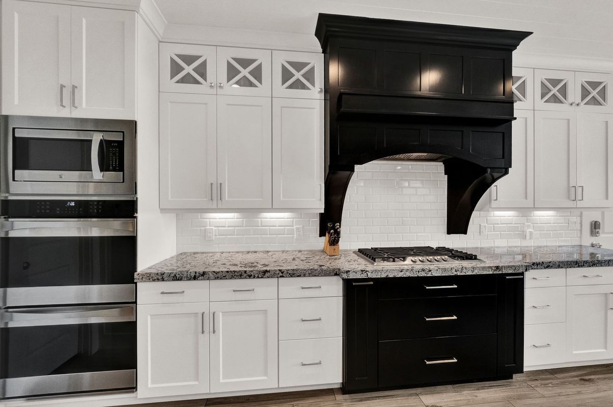 A kitchen with white cabinets and black appliances and a stove top oven.