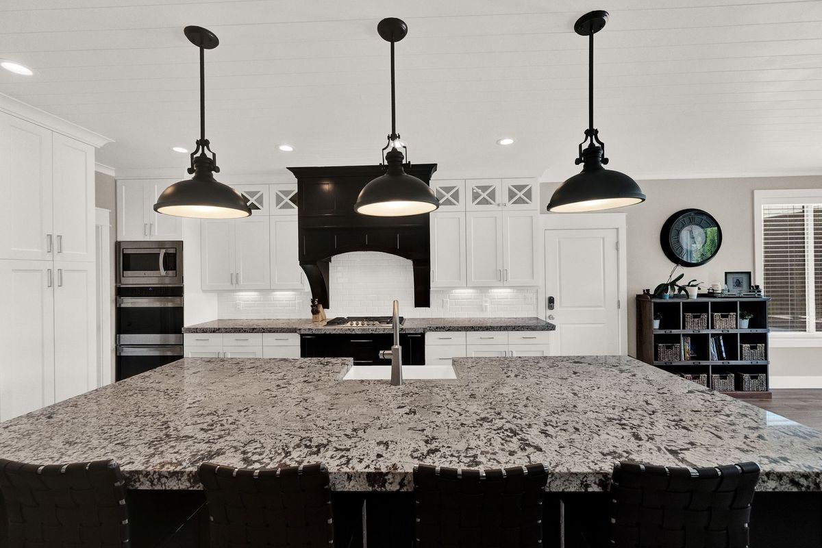 A kitchen with a large island and three pendant lights hanging from the ceiling.