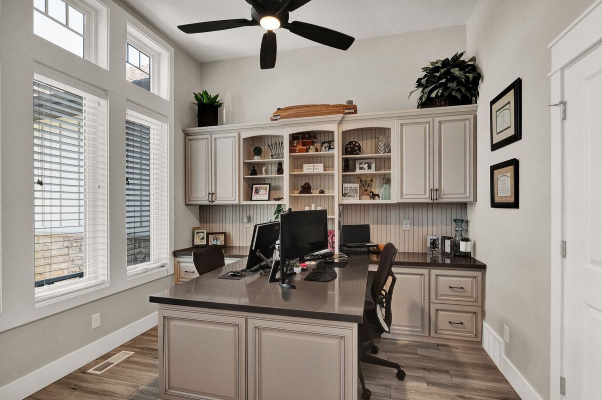 A home office with a desk , chair , computer and ceiling fan.
