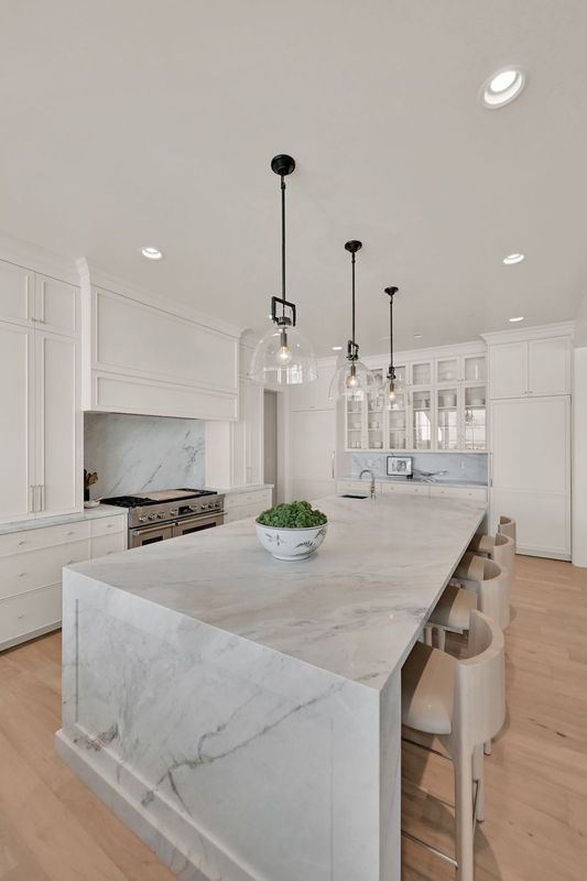 A kitchen with a large island and marble counter tops.
