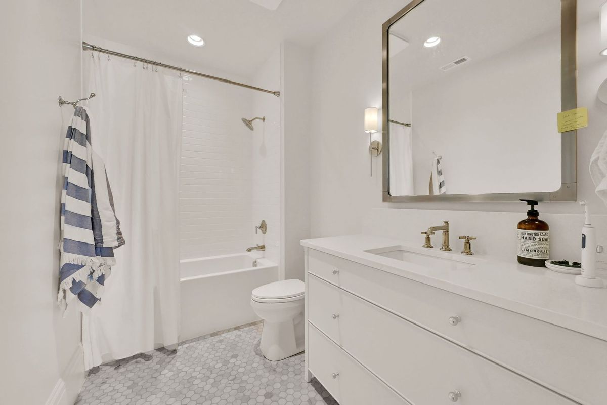 A bathroom with a toilet , sink , mirror and bathtub.