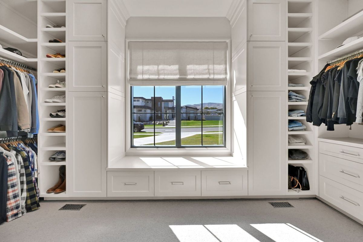A walk in closet with lots of clothes and a window