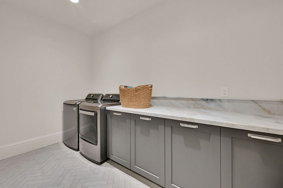 A laundry room with a washer and dryer and a basket on the counter.