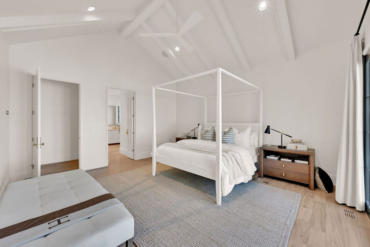 A bedroom with a canopy bed and a bench.