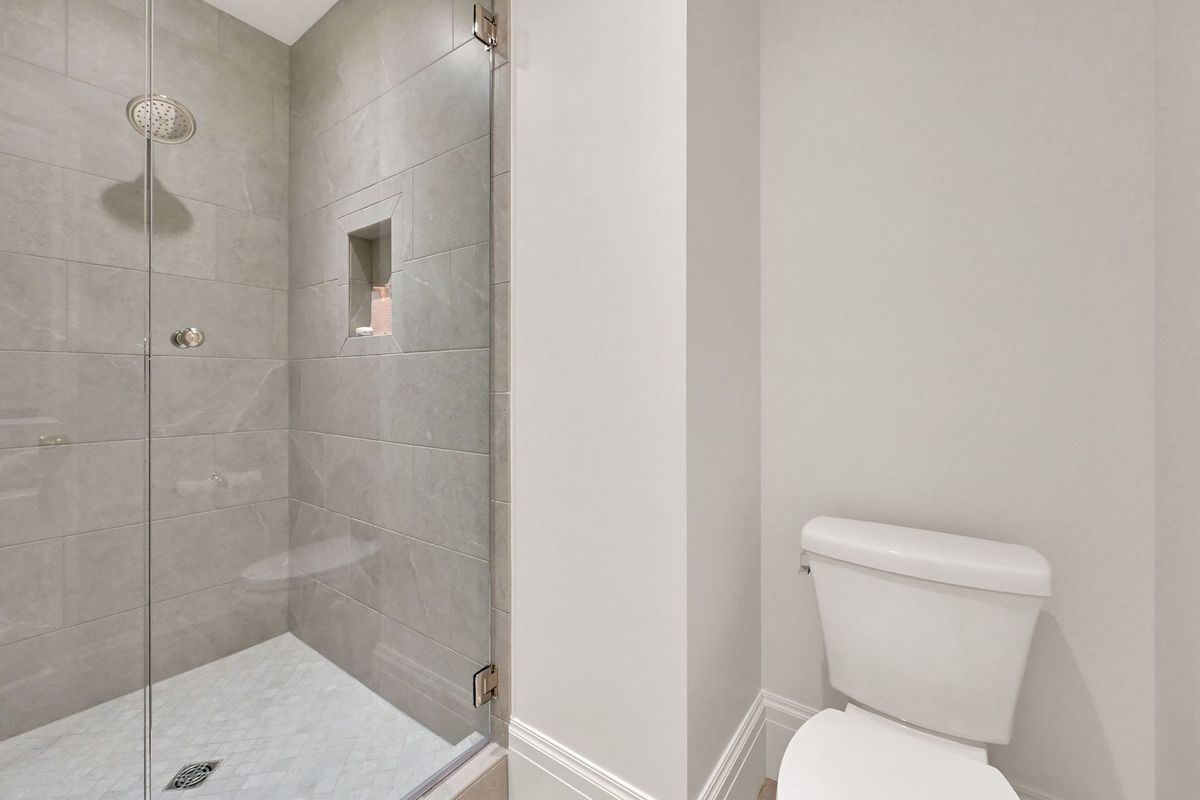 A bathroom with a toilet and a shower with a glass door.