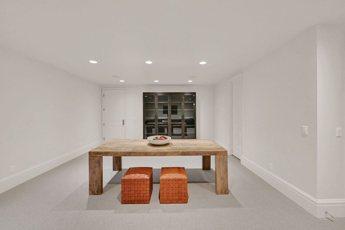 A dining room with a wooden table and two orange ottomans.