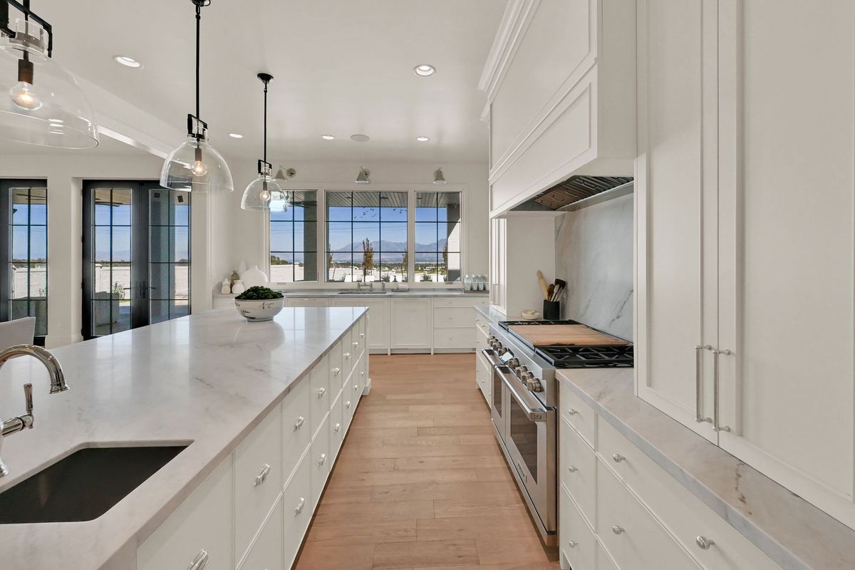 A kitchen with white cabinets , granite counter tops , stainless steel appliances and a large island.