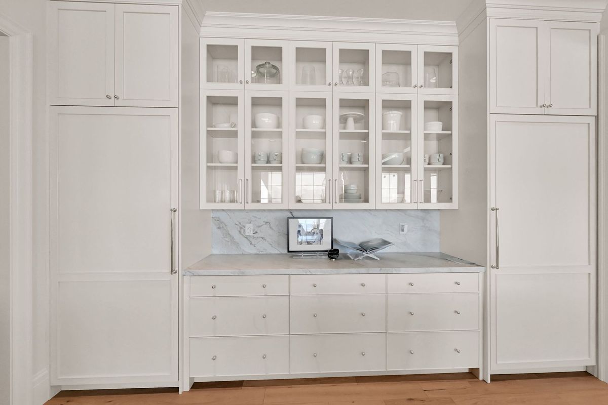 A kitchen with white cabinets and a laptop on the counter.