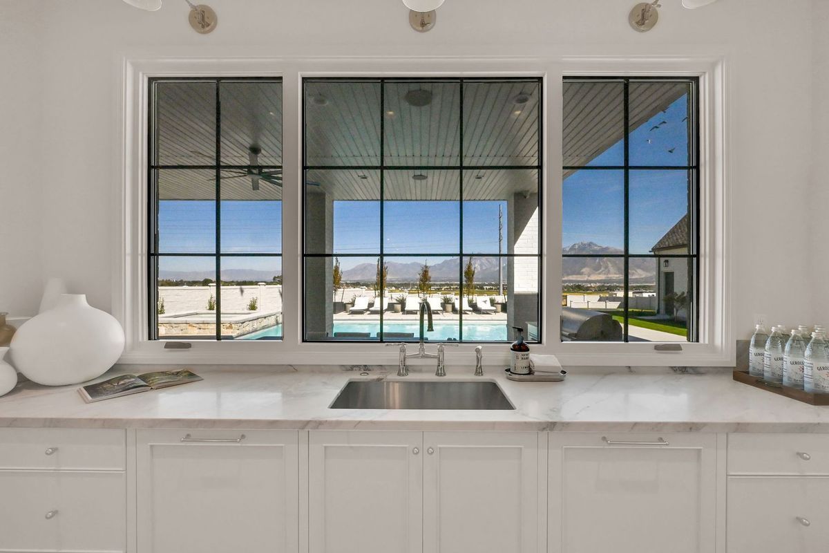 A kitchen with a sink and a large window with a view of a pool.