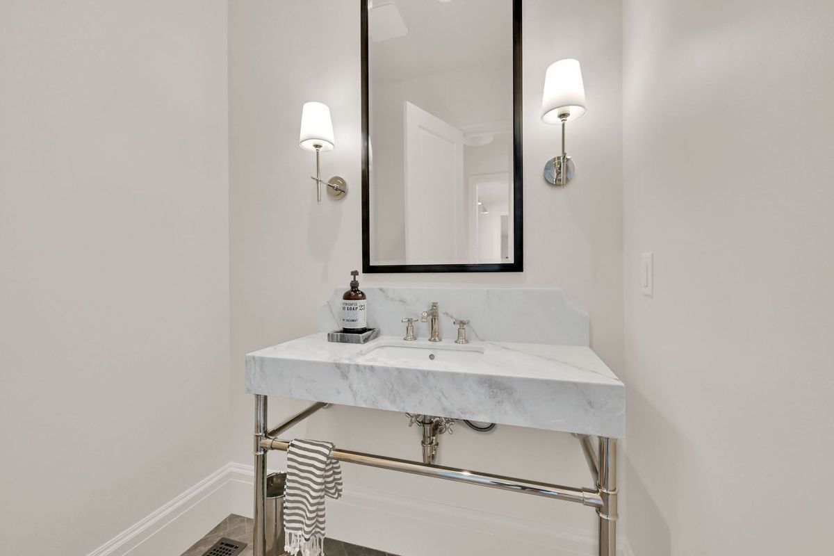 A bathroom with a sink , mirror and lights.