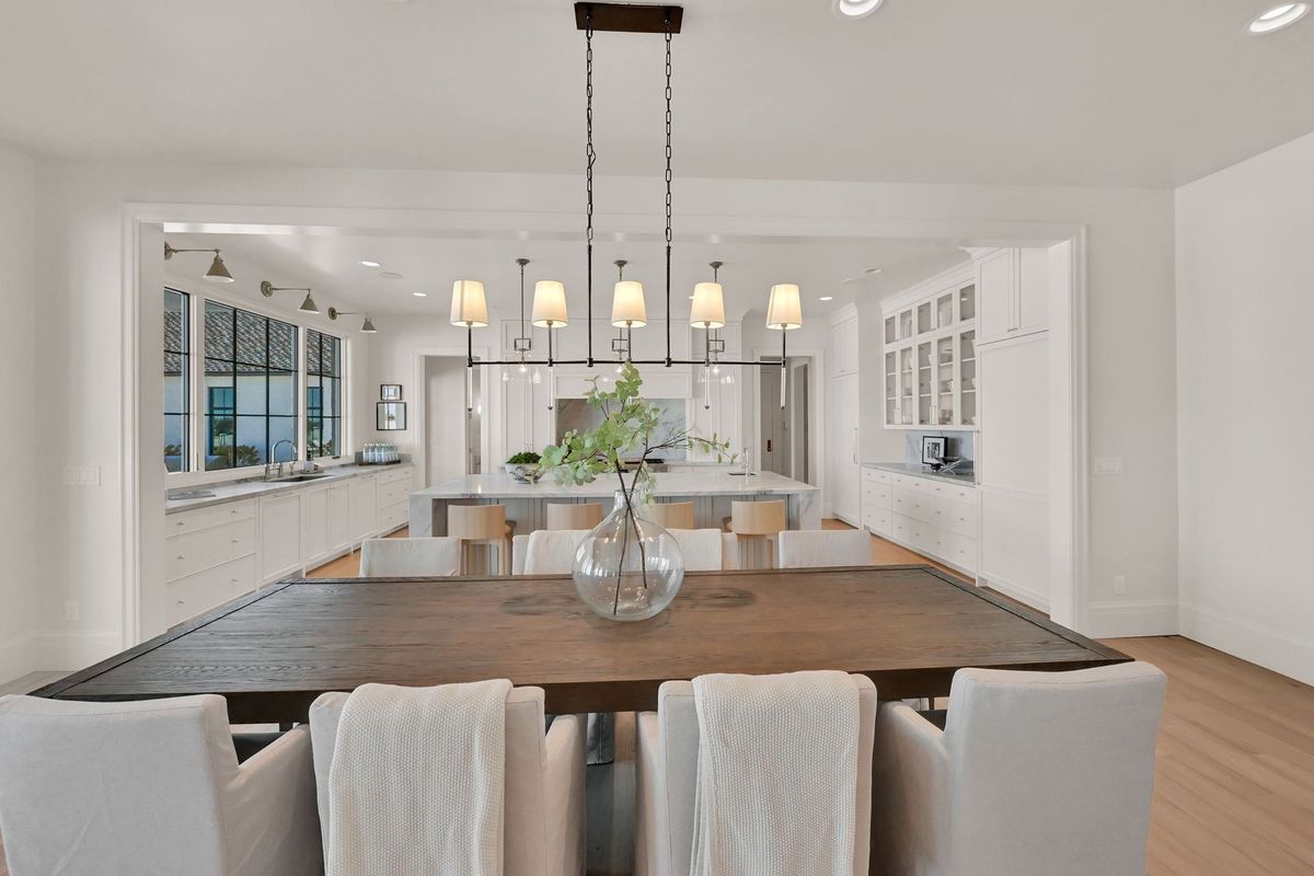 A dining room with a table and chairs and a vase on the table.